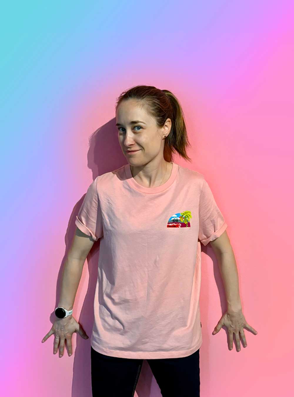 Photograph of Rebecca wearing a pink t-shirt, set against a solid pink background, creating a monochromatic aesthetic.